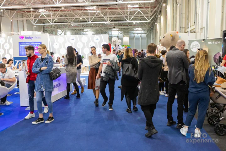 Vizitatori pe culoarul dintre standuri, în pavilion