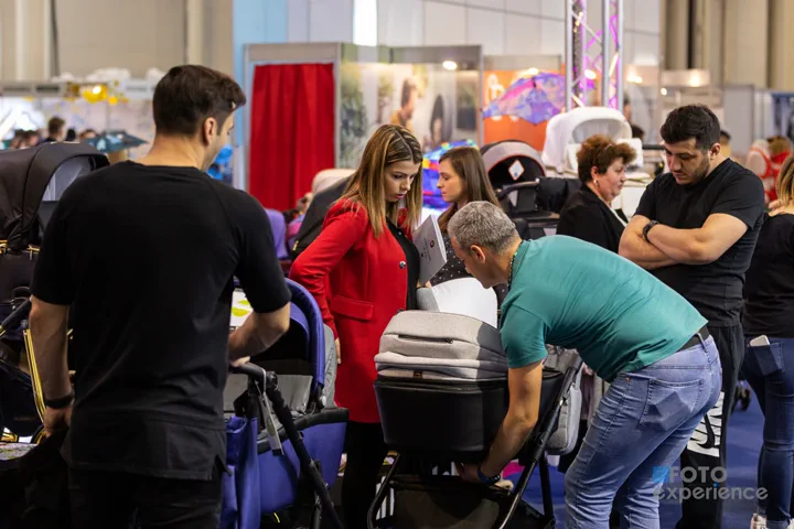 Familii care încearcă cărucioare la standul unui expozant