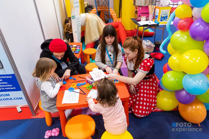 Atelier creativ pentru copii, cu mese de lucru și baloane colorate