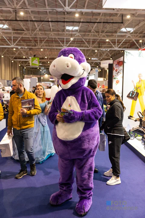 Mascotă costumată care întâmpină vizitatorii printre standuri