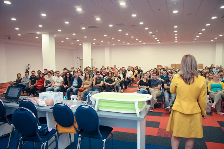 Conferință în sală plină, cu produse expuse în fața publicului