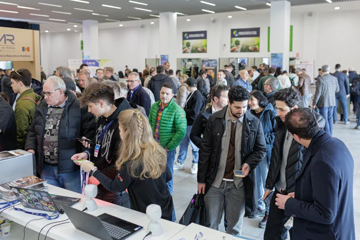 Vizitatori adunați la un stand din pavilion